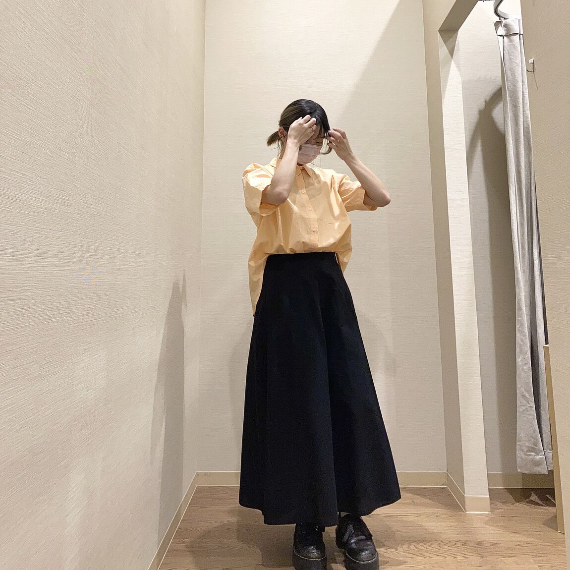 オレンジのシャツと黒のフレアスカートを着用した女性