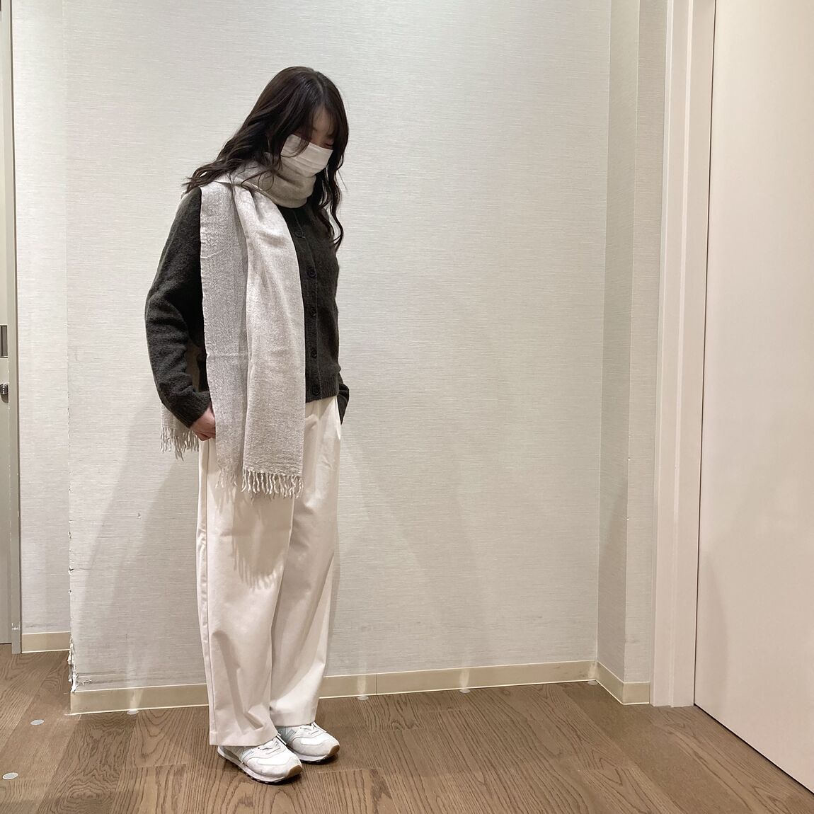 カーキのニットとベージュのマフラーを着用した女性