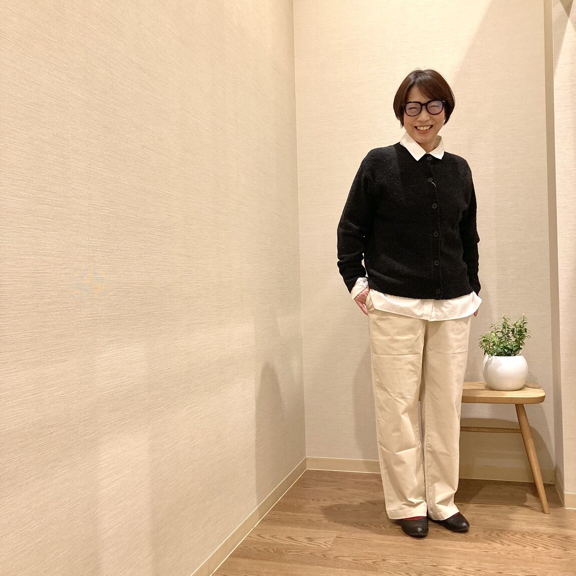 白のパンツとチャコールグレーのカーディガンを着用した女性