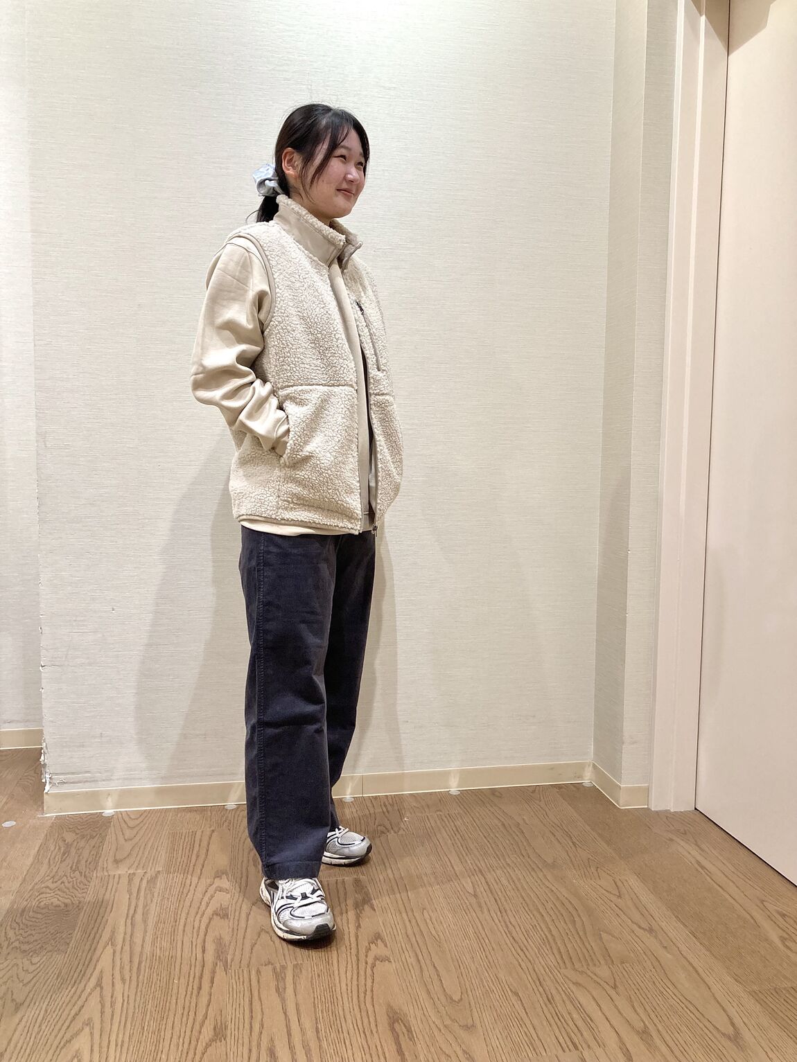 ベージュのスウェットシャツとベージュのボアベストを着用した女性　