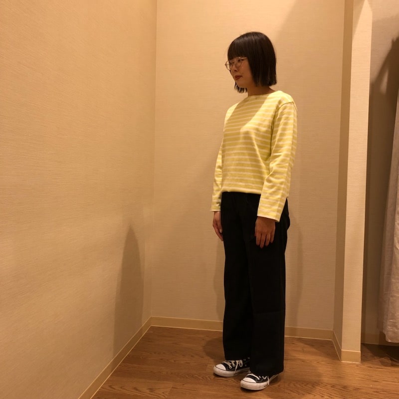 黄色のボーダーのトップスにネイビーのボトムスを着用した女性の写真