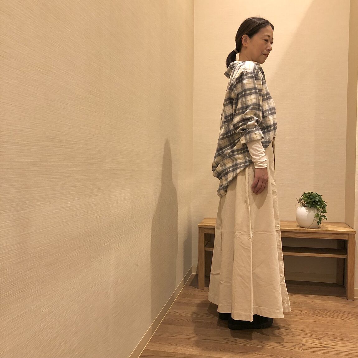 チェックのシャツと白いスカートを着た女性