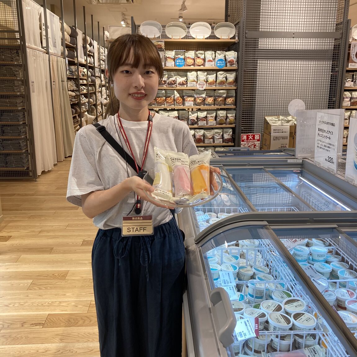 皿に乗せたアイスキャンデーを持って微笑むスタッフの写真
