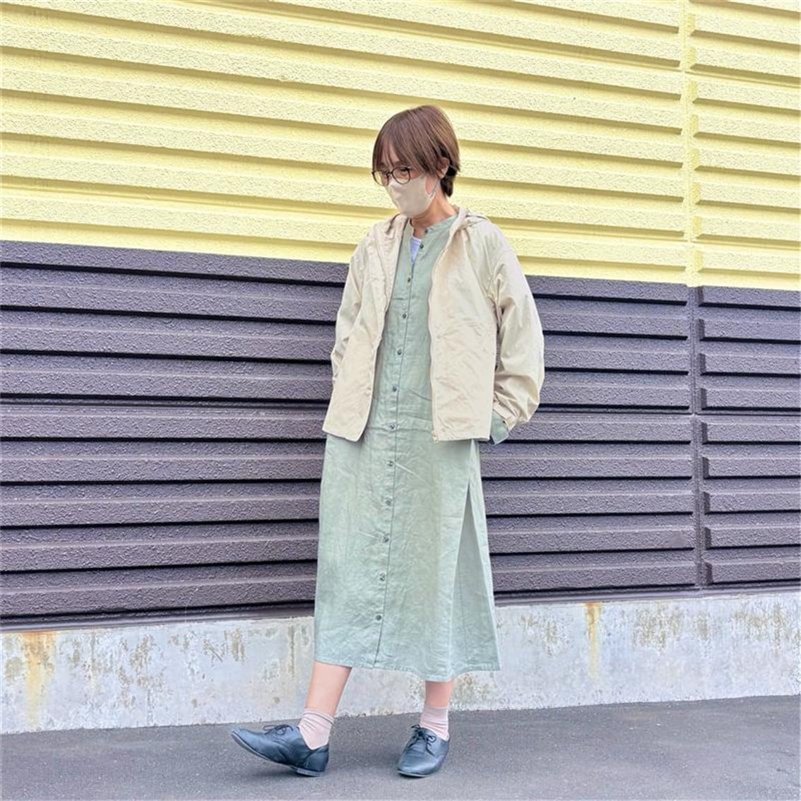リネンの洗いざらし長袖シャツワンピースに撥水のフードジャケットを合わせたコーディネートのスタッフの写真です。