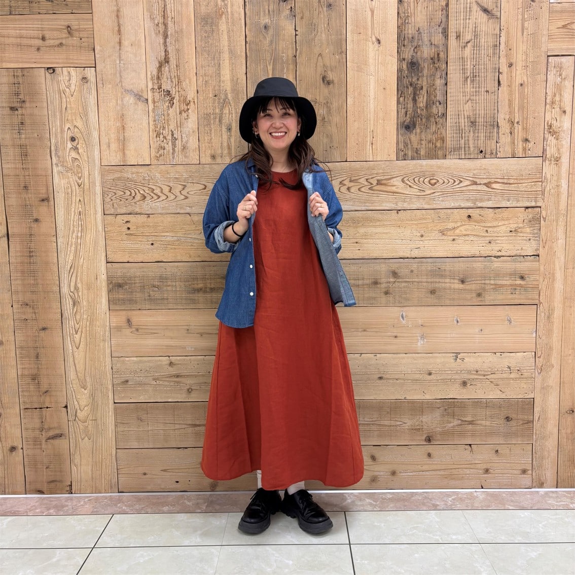 リネンの洗いざらしスリーブレスワンピースにデニムシャツを合わせたコーディネートのスタッフの写真です。