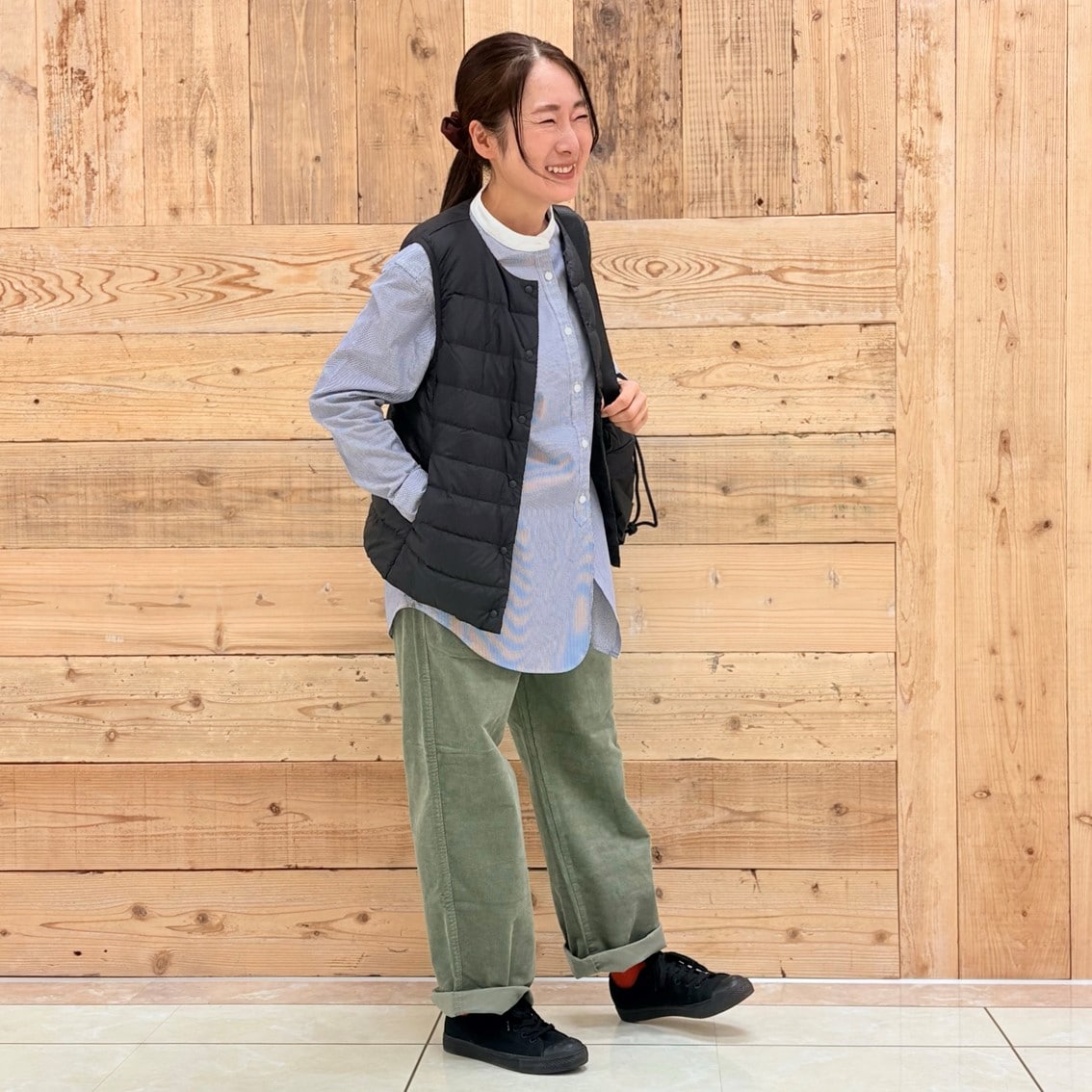 コーデュロイパンツにスタンドカラーロングシャツ、ベストを合わせたコーディネートのスタッフ写真です。