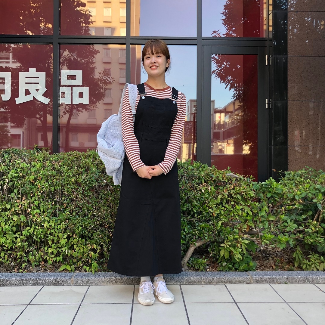 女性がスカートをはいて立っている写真。