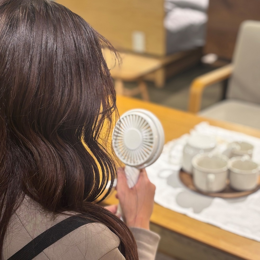 女性がハンディファンから風を受けている様子