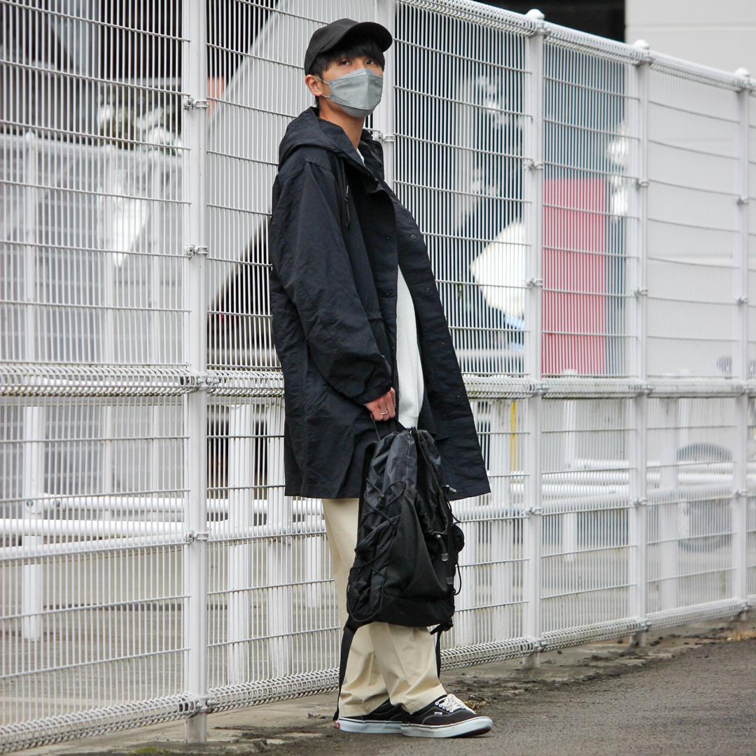 コートを着てフェンスに寄り掛かった写真です