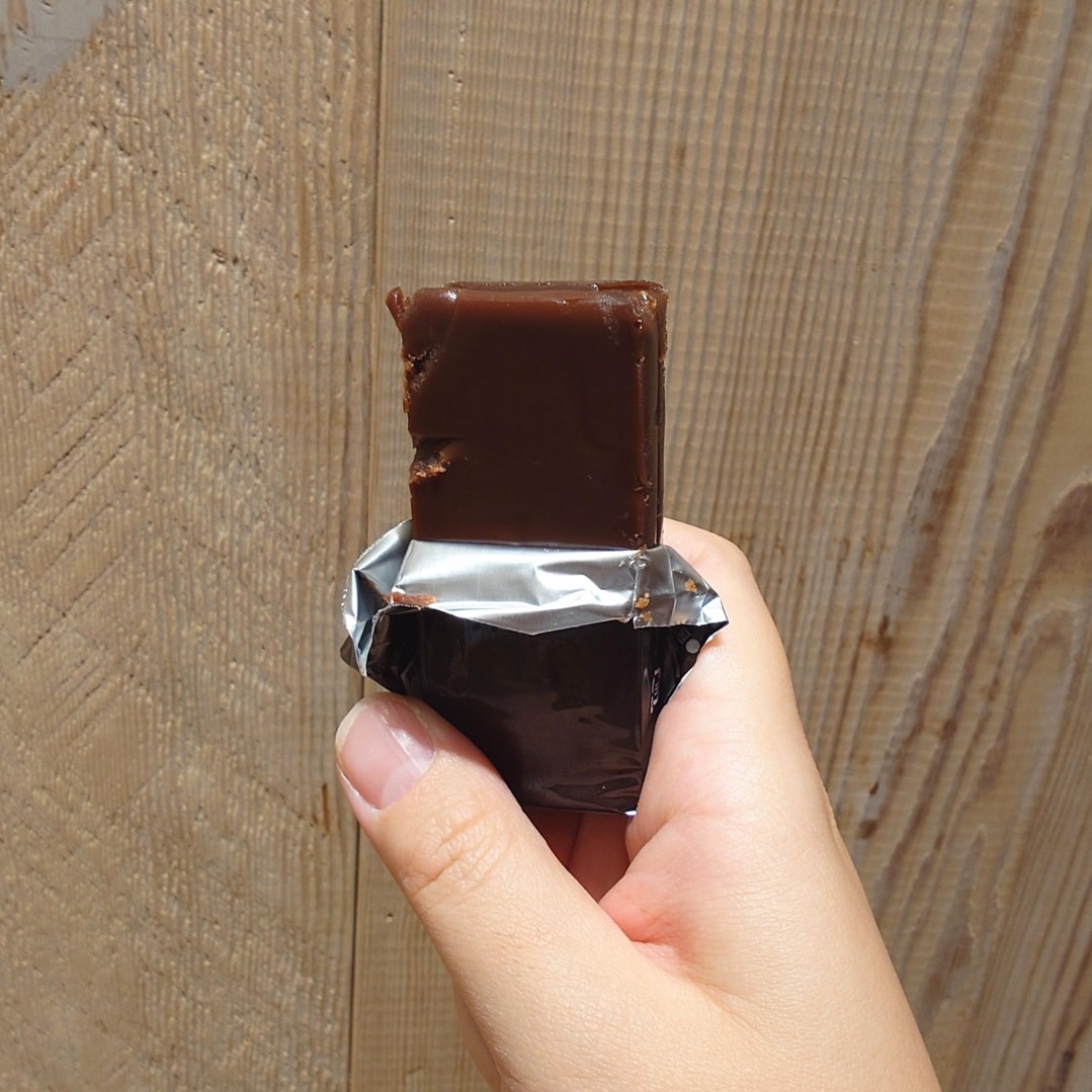 【テラスモール湘南】個包装のチョコようかんのフィルムを開封し、中身を半分出した状態で手に持った写真