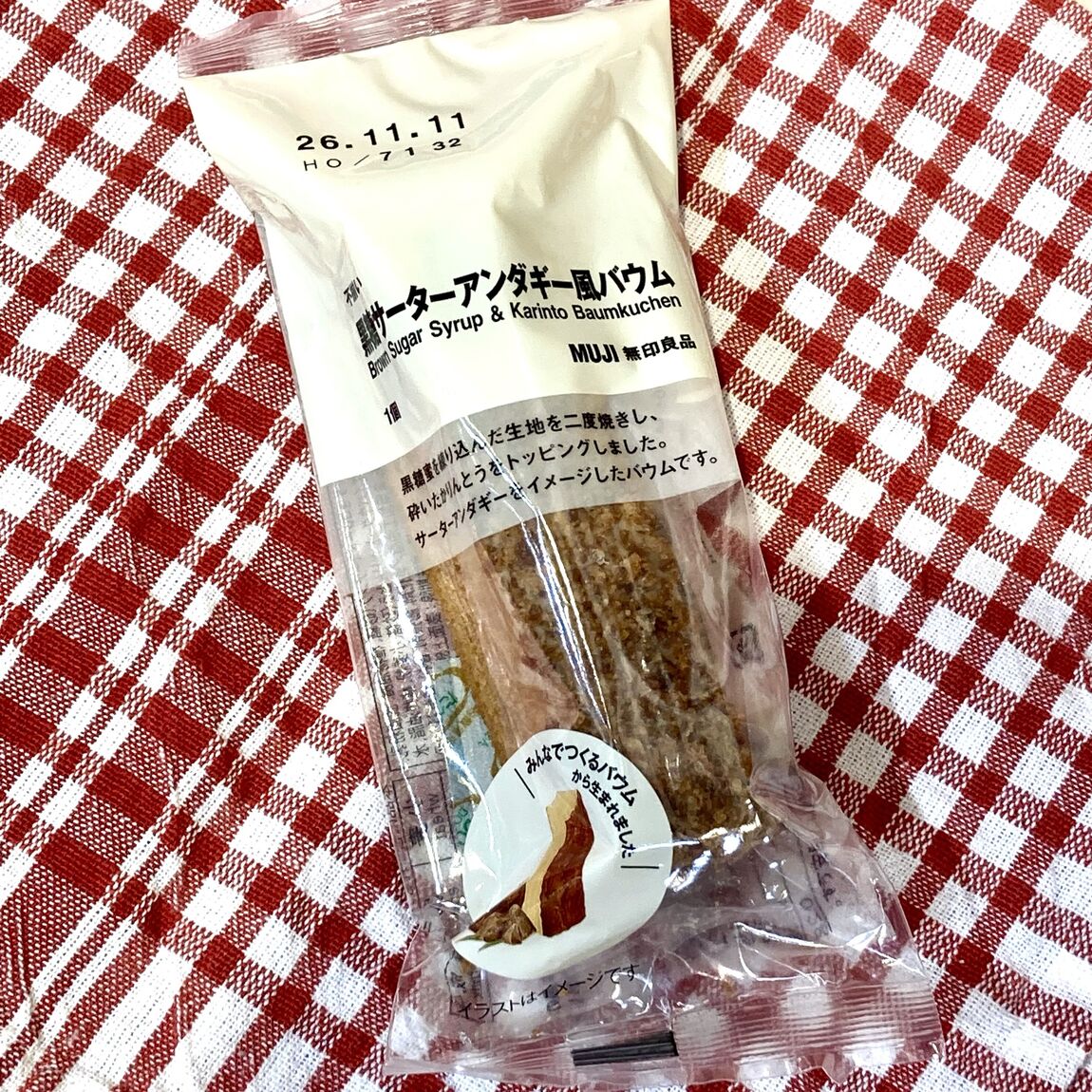 【テラスモール湘南】赤いチェックのクロスの上に袋入りの黒糖サーターアンダギー風バウムを乗せた写真