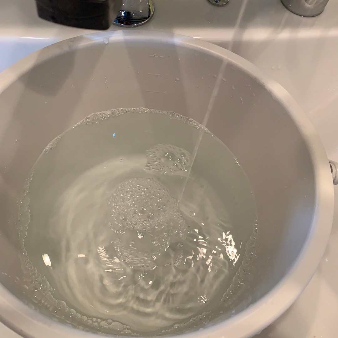 容器に40℃くらいのお湯を入れて、衣料用洗剤をよく溶かします。