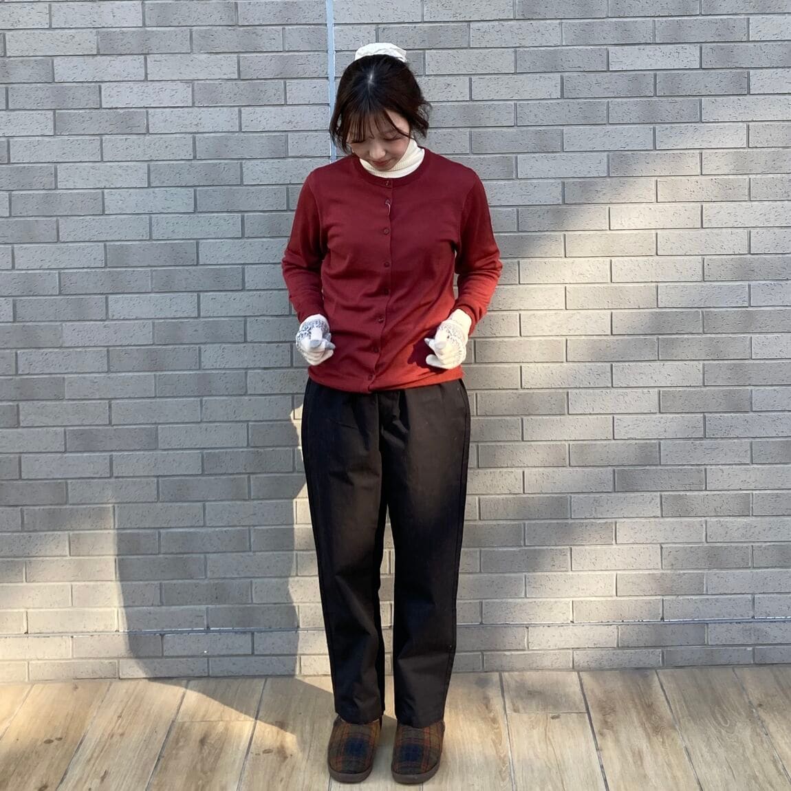 赤いセーター、黒いパンツ、白い手袋の女性