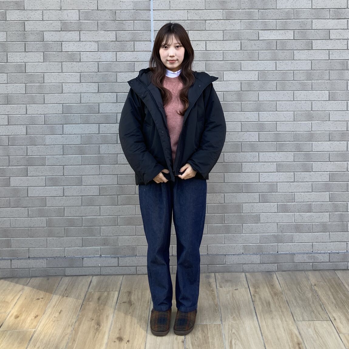 黒いジャケット、ピンクのセーター、デニムパンツの女性