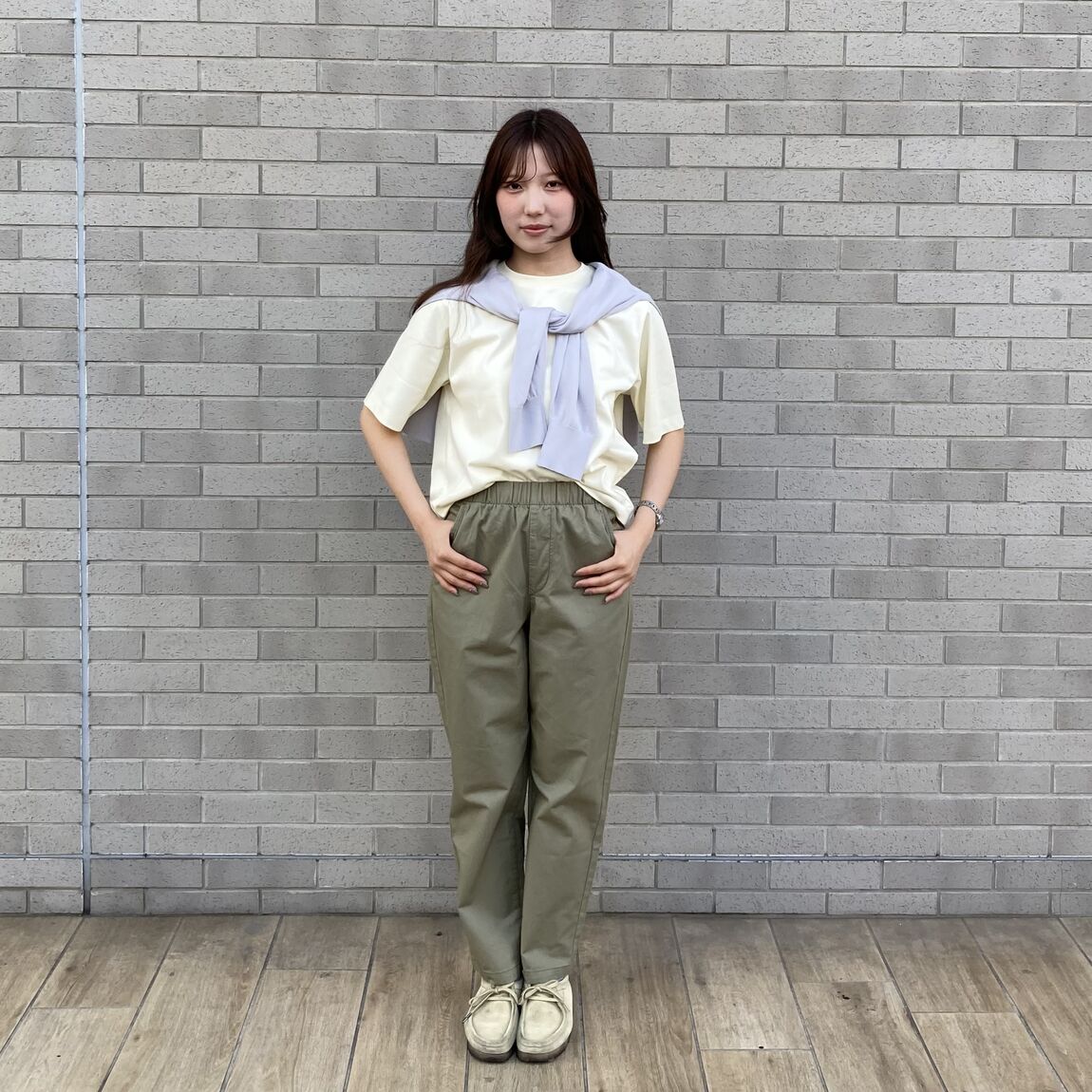 黄色のＴシャツとカーキのパンツ、灰色のカーディガンを肩からかけているコーデ