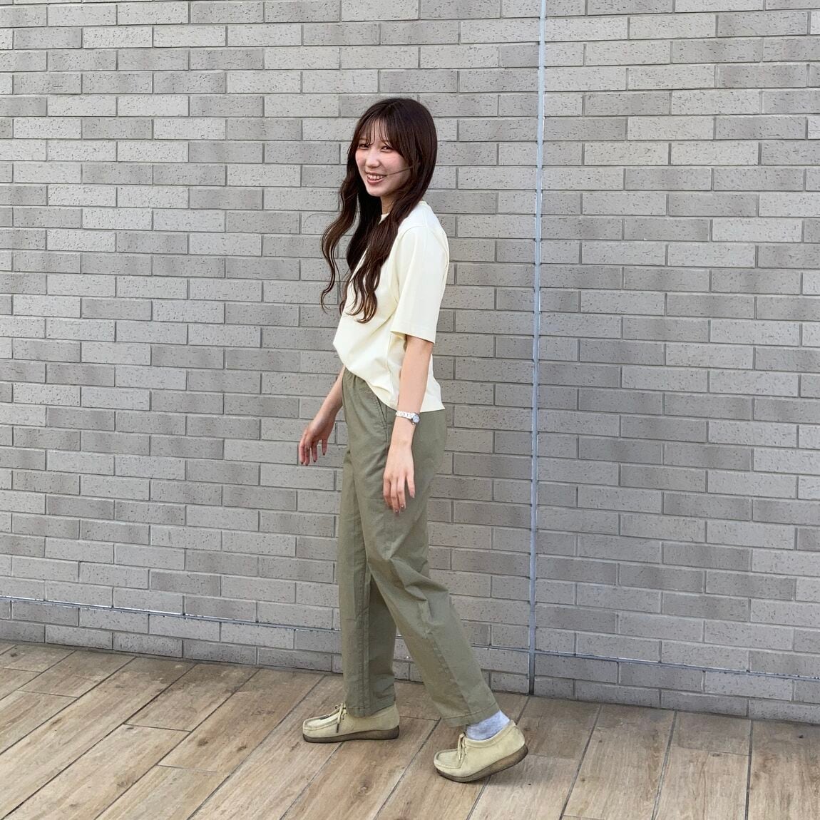 黄色のＴシャツとカーキのパンツのコーデ。歩いている写真