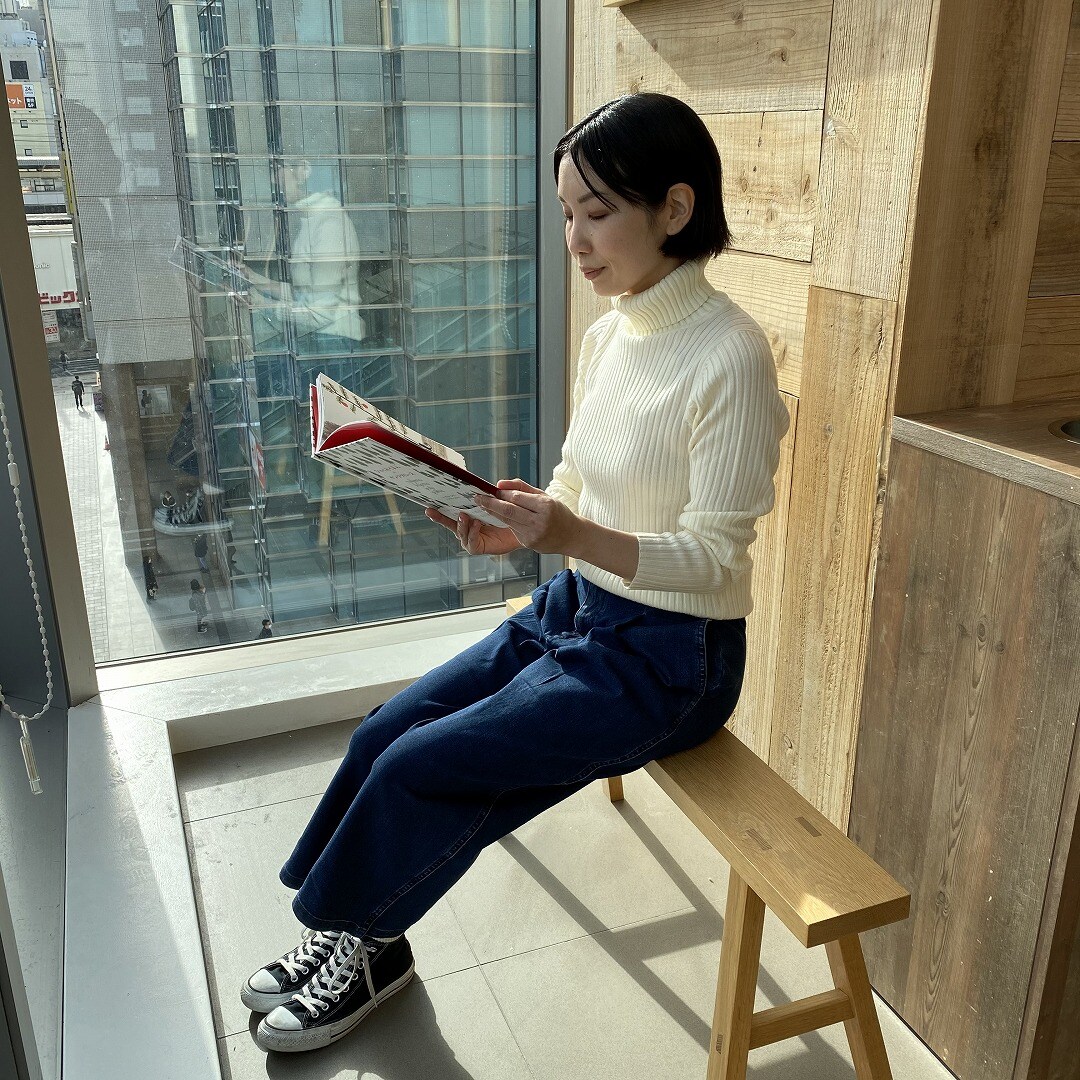 タートルネックセーターを着て本を読む女性スタッフ