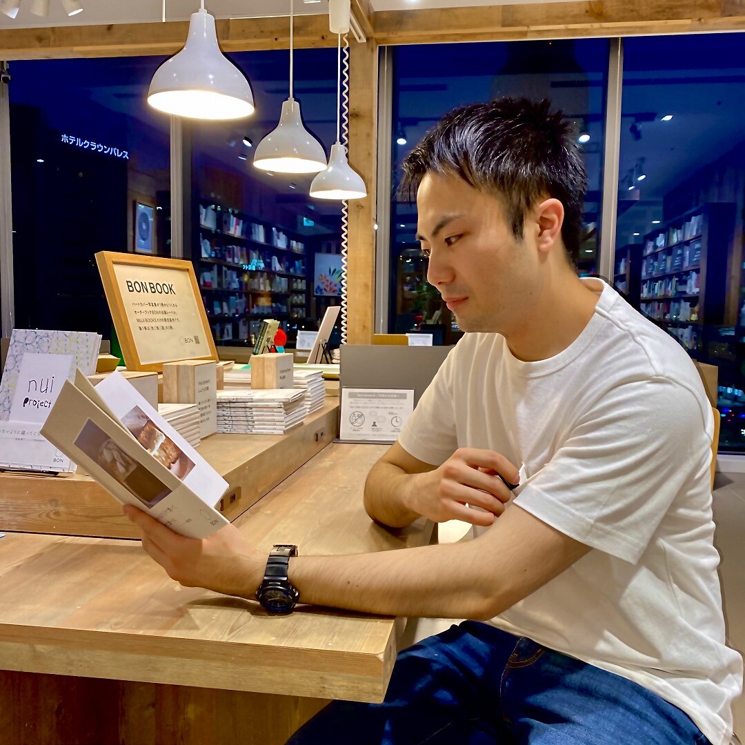 男性スタッフがTシャツをきて本を読んでいる画像