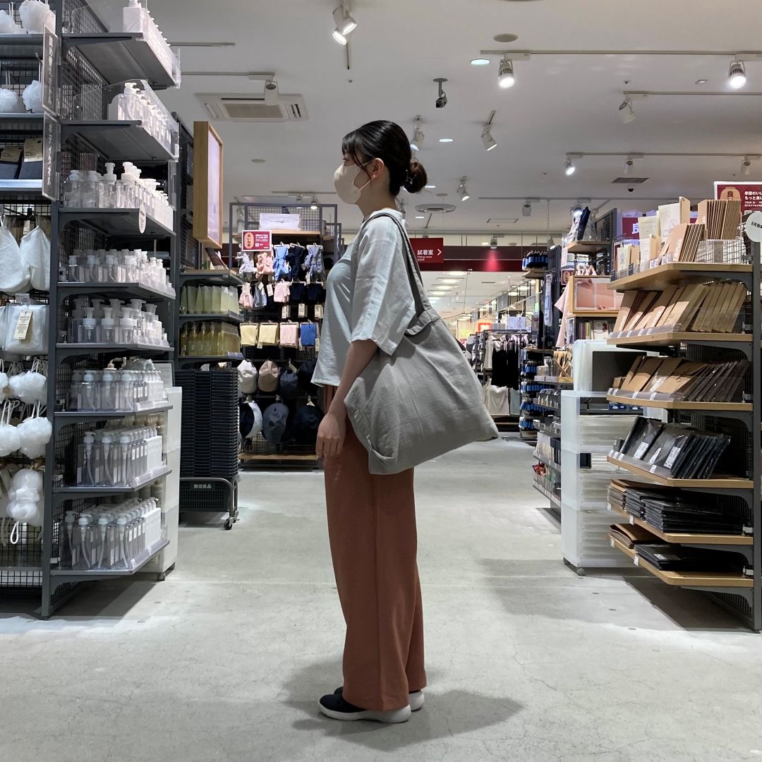 風を通すイージーパンツとなめらか五分袖ブラウスを着たスタッフの横向きの写真