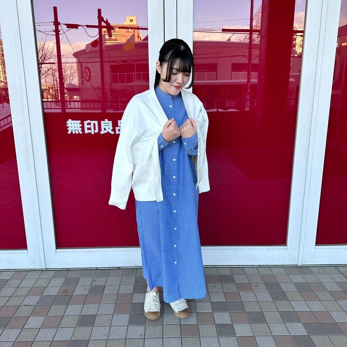 上からカーディガンを羽織るスタンドカラーワンピースを着た女性スタッフ