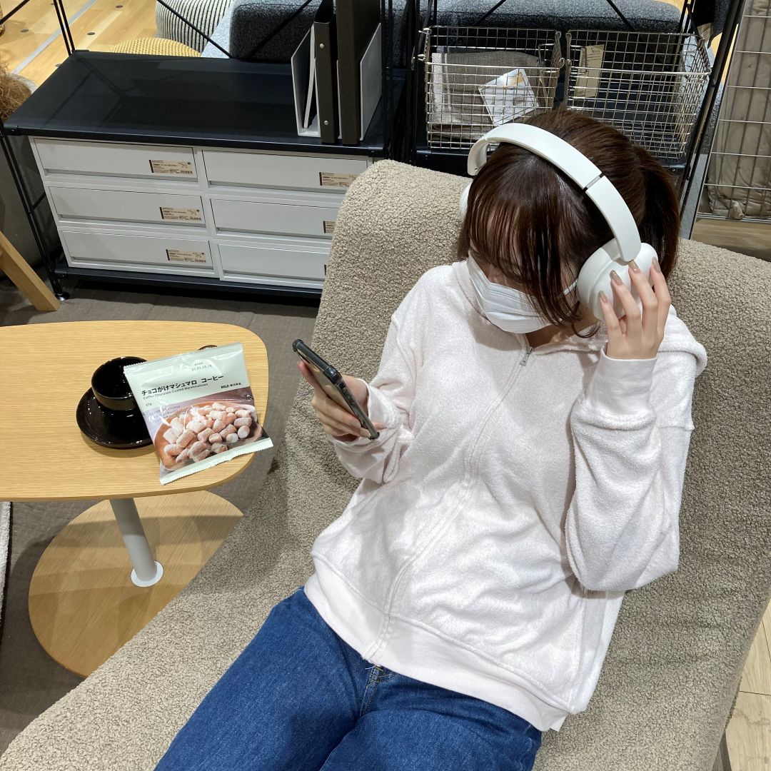 ヘッドホンをつけた女性がソファに座っている写真