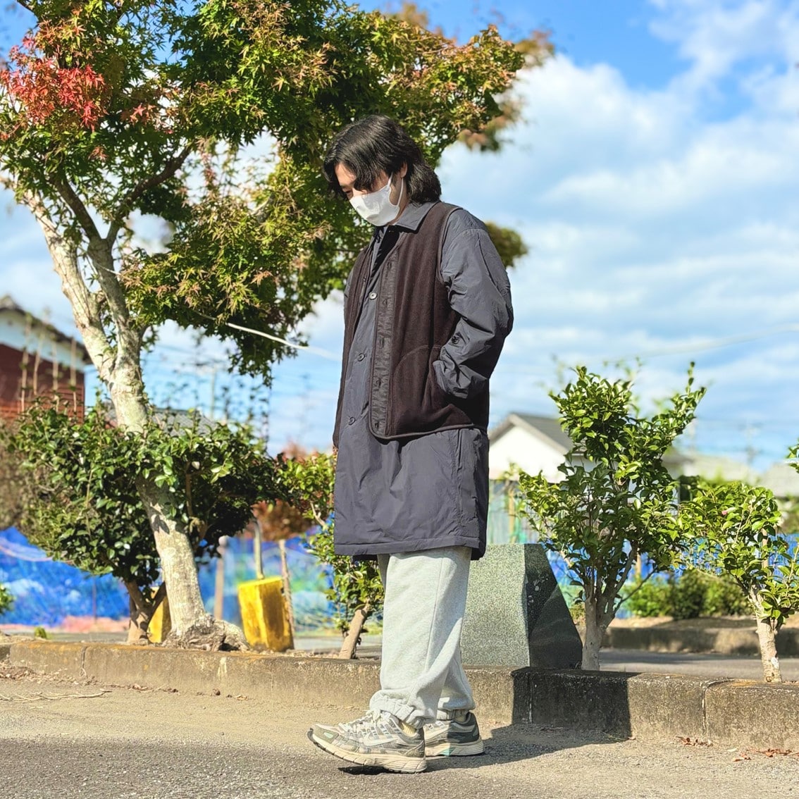 ステンカラーコートの上にフリースベストを合わせたコーディネートのスタッフの写真です。