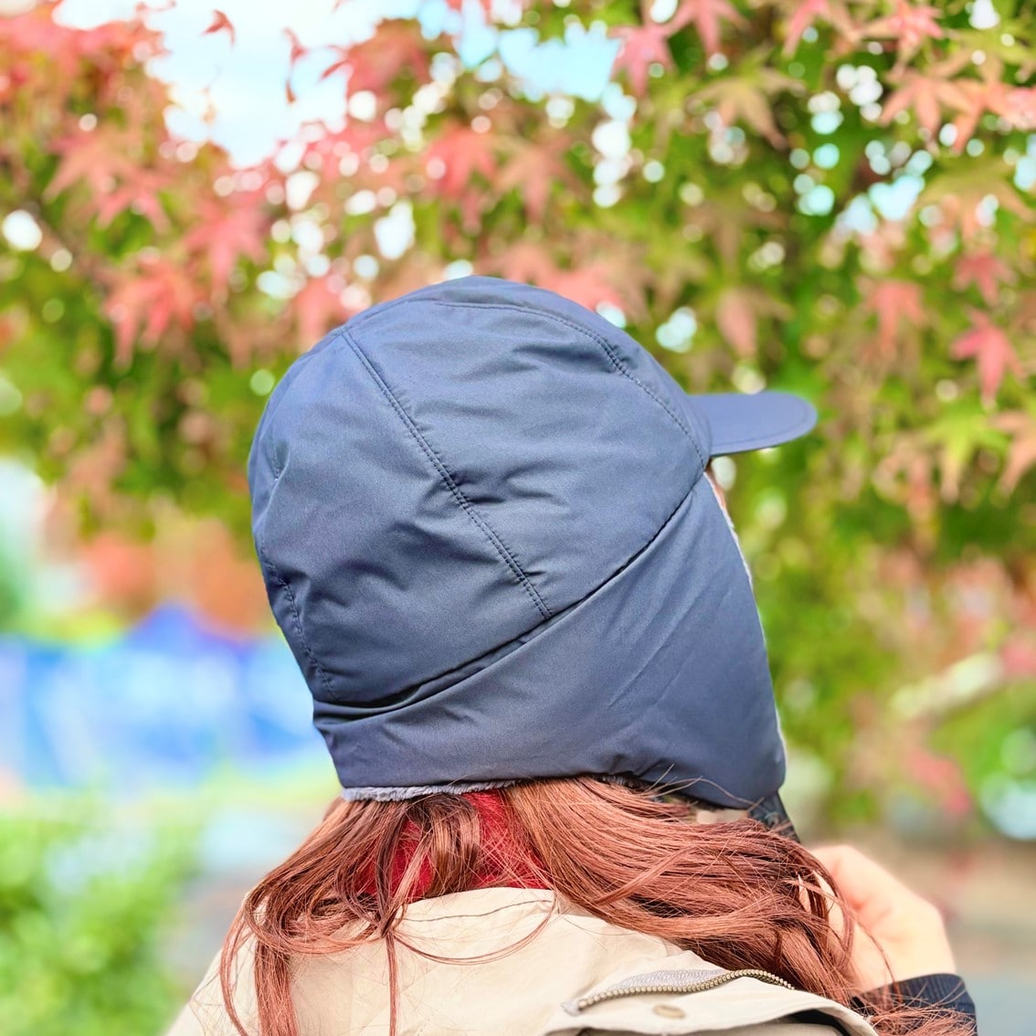 フライトキャップと赤いマフラーでカジュアルにコーディネートしたスタッフの写真です。