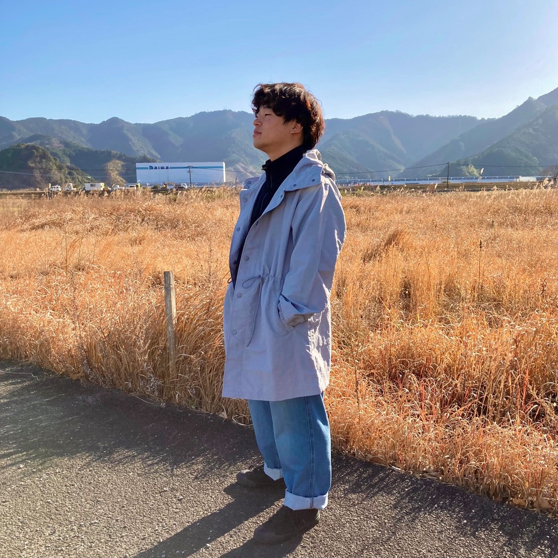 ハーフジップスウェットシャツに撥水フード付きコートを合わせたコーディネートのスタッフの写真です。