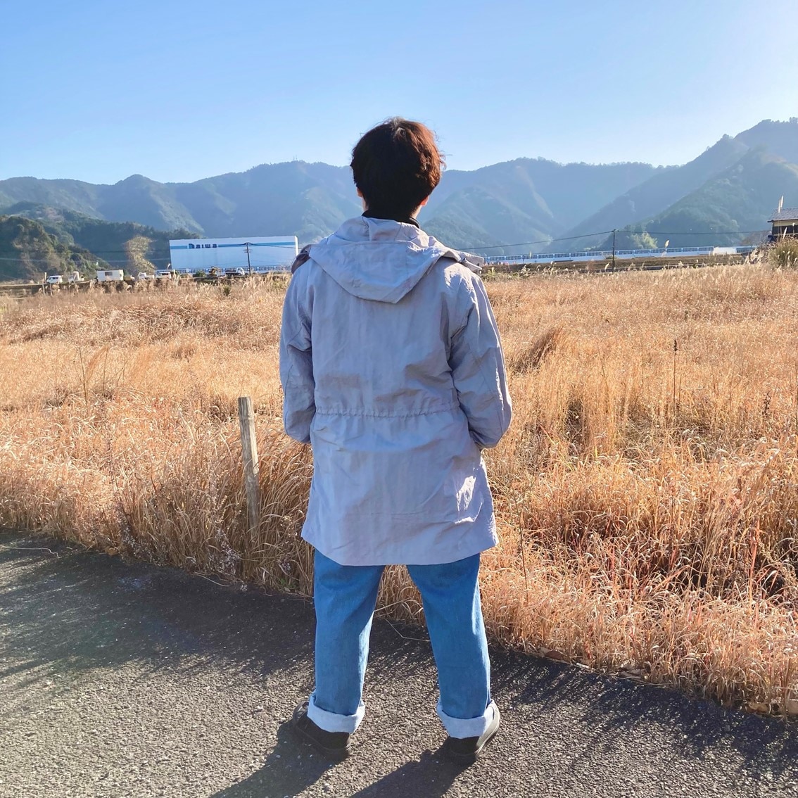 ハーフジップスウェットシャツに撥水フード付きコートを合わせたコーディネートのスタッフの写真です。