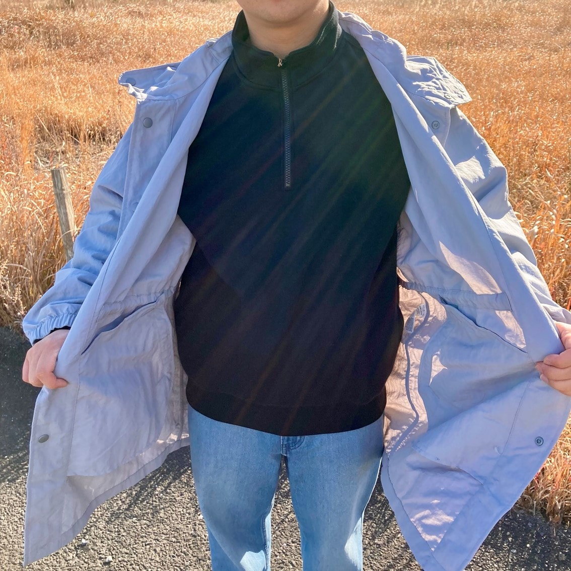 ハーフジップスウェットシャツに撥水フード付きコートを合わせたコーディネートのスタッフの写真です。