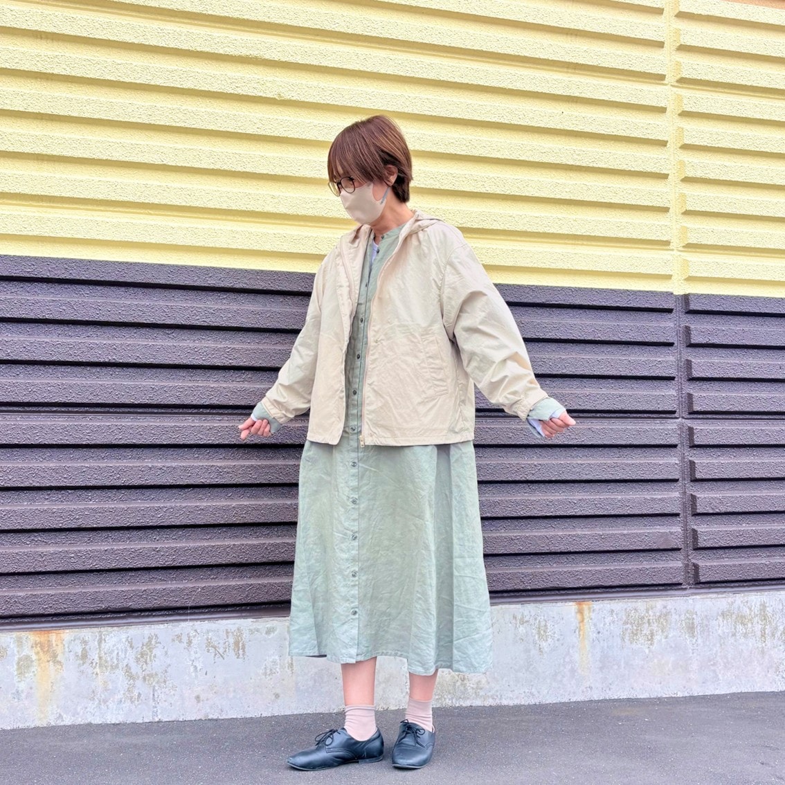 リネンの洗いざらし長袖シャツワンピースに撥水のフードジャケットを合わせたコーディネートのスタッフの写真です。