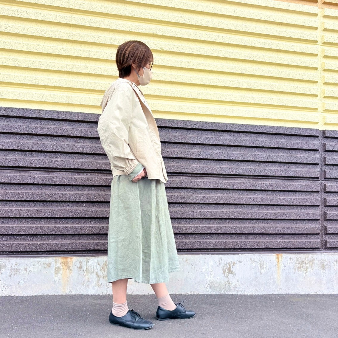 リネンの洗いざらし長袖シャツワンピースに撥水のフードジャケットを合わせたコーディネートのスタッフの写真です。