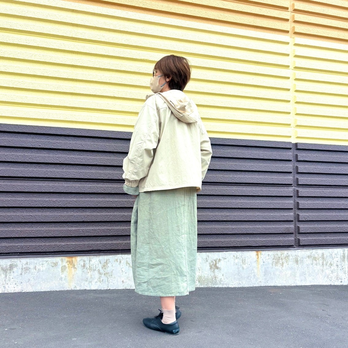 リネンの洗いざらし長袖シャツワンピースに撥水のフードジャケットを合わせたコーディネートのスタッフの写真です。