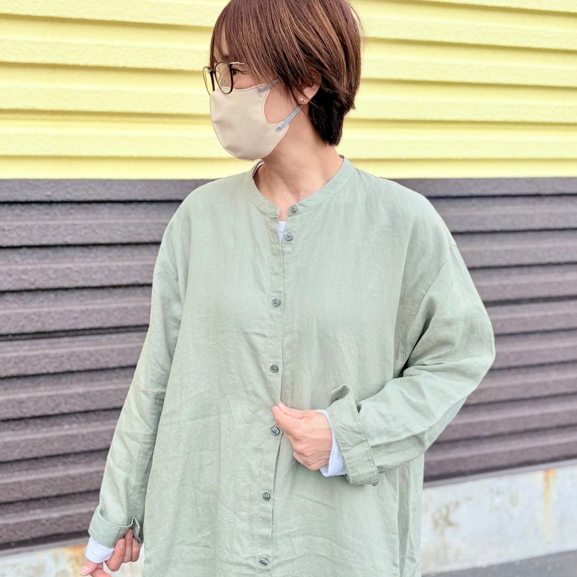 リネンの洗いざらし長袖シャツワンピースに撥水のフードジャケットを合わせたコーディネートのスタッフの写真です。