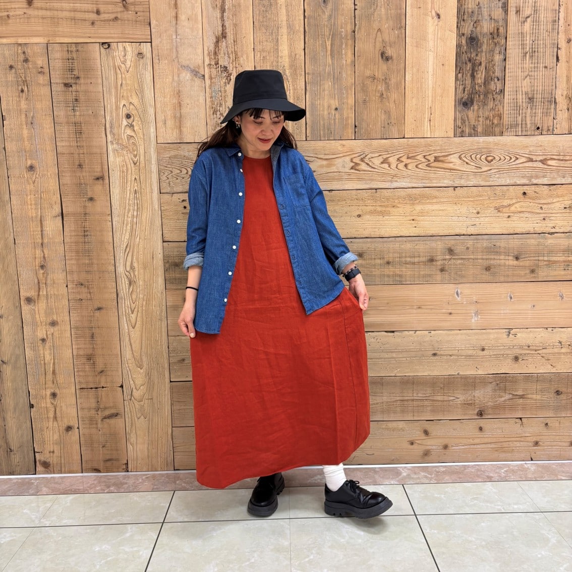 リネンの洗いざらしスリーブレスワンピースにデニムシャツを合わせたコーディネートのスタッフの写真です。