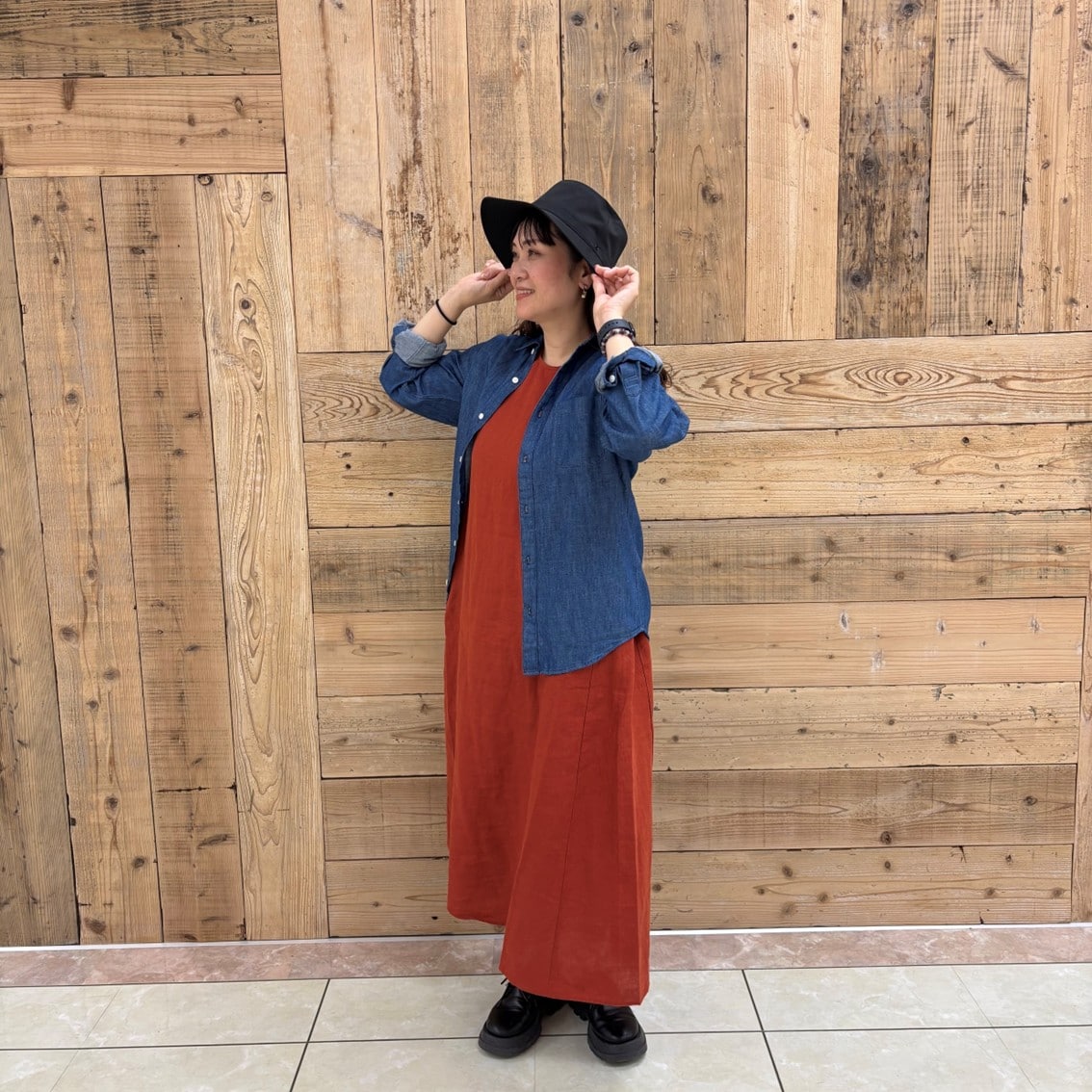 リネンの洗いざらしスリーブレスワンピースにデニムシャツを合わせたコーディネートのスタッフの写真です。