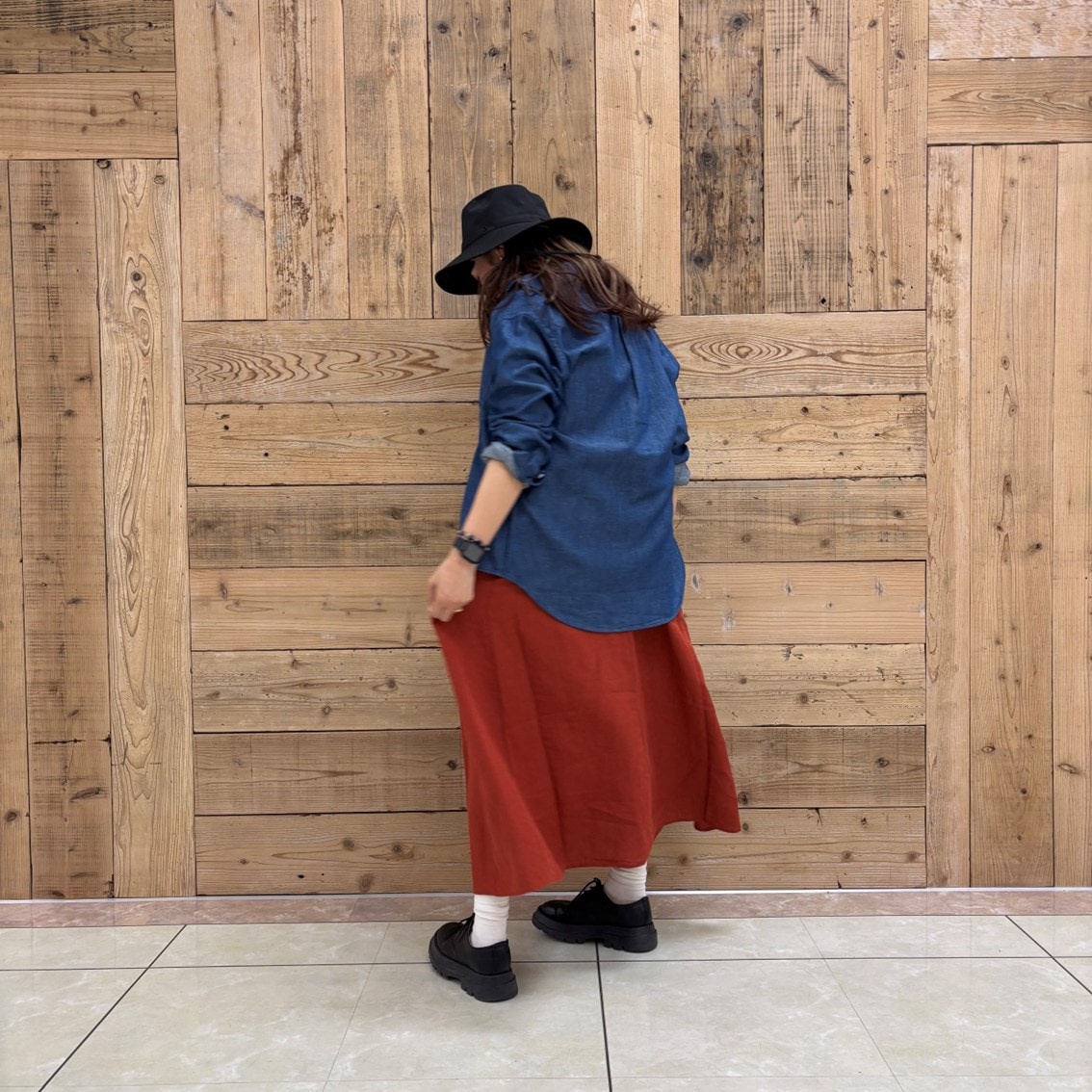 リネンの洗いざらしスリーブレスワンピースにデニムシャツを合わせたコーディネートのスタッフの写真です。