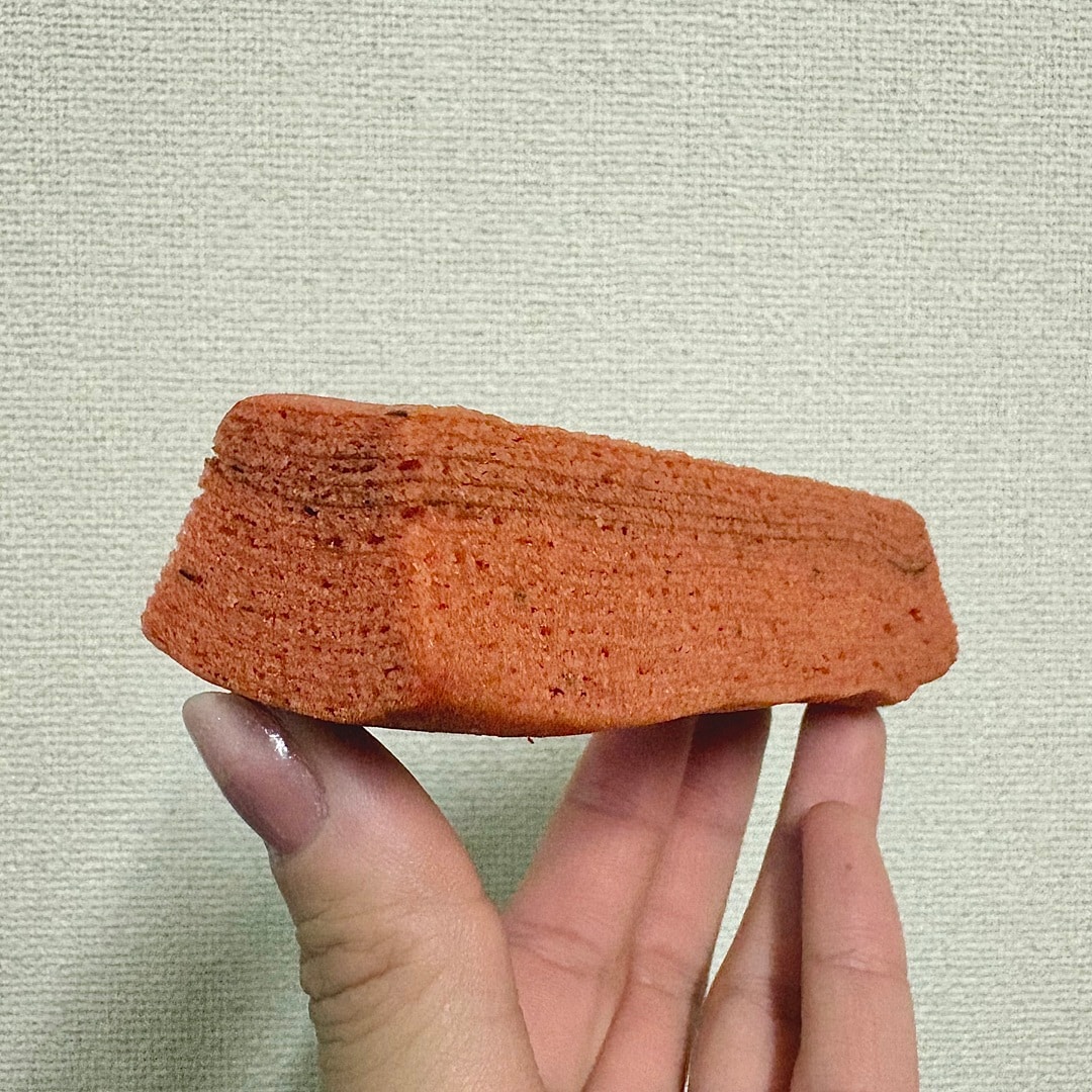 「食物繊維がとれるバウム　トマト＆バジル」の中身を手にもったイメージ画像