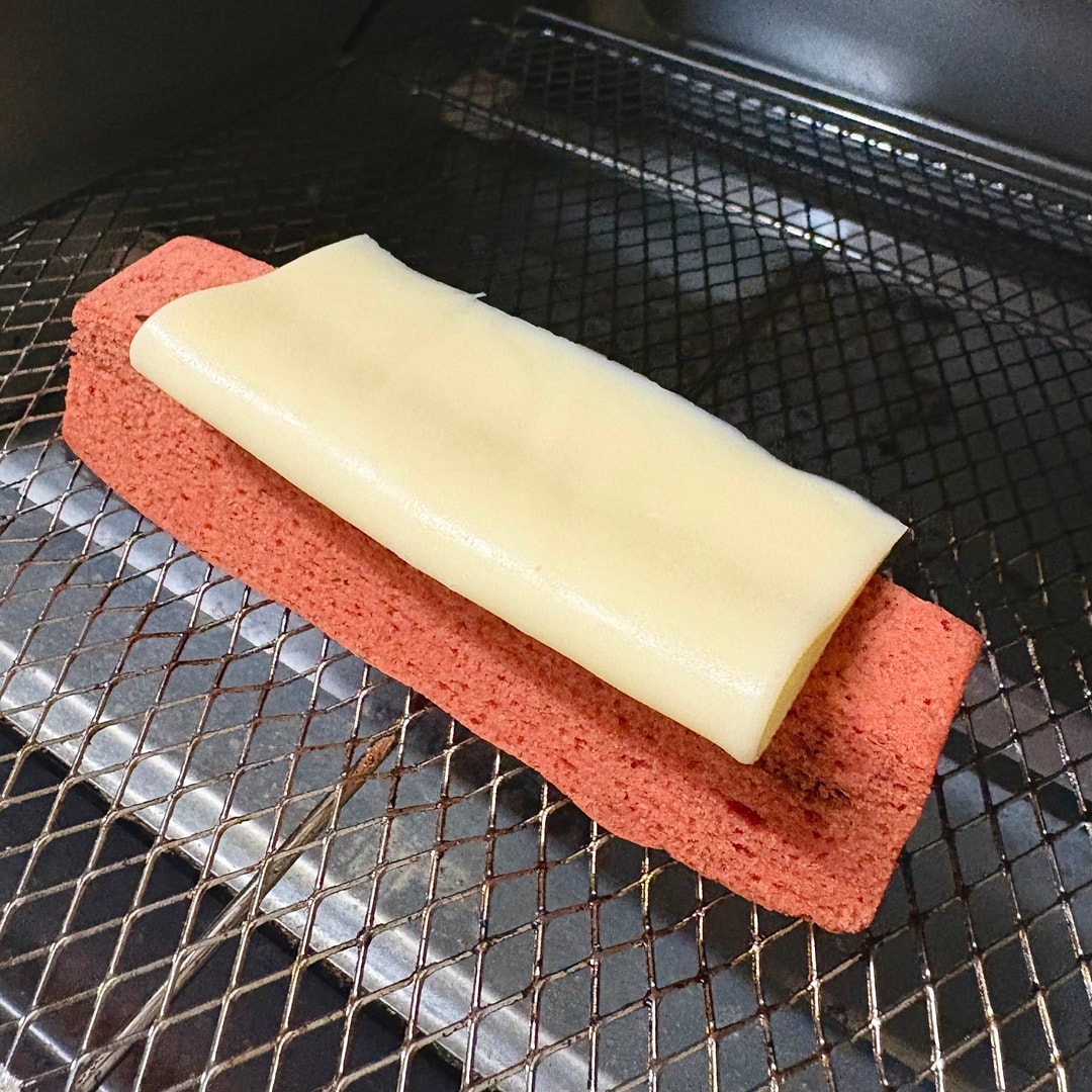 「とろけるチーズ」を乗せた「食物繊維がとれるバウム　トマト＆バジル」をトースターで焼くイメージ画像