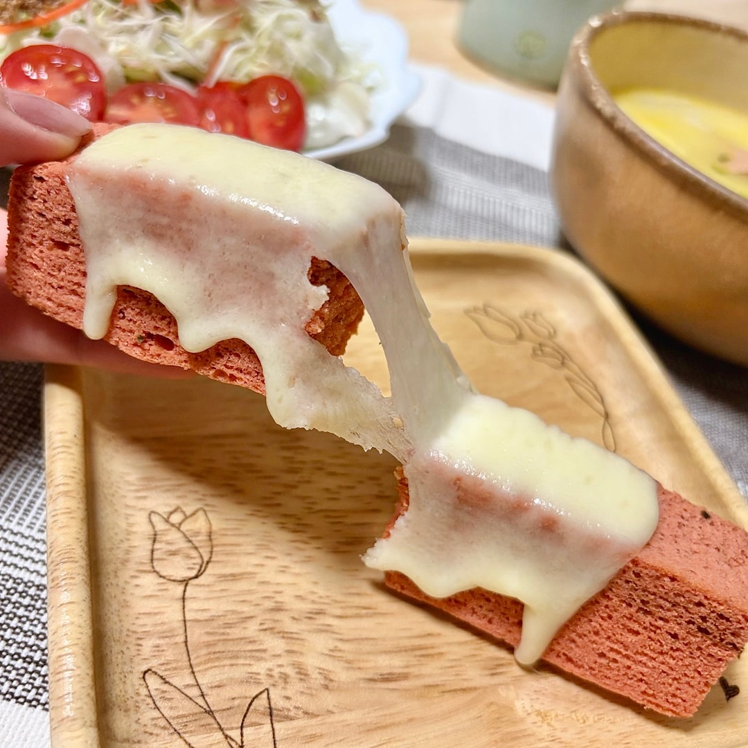 チーズをのせた「食物繊維がとれるバウム　トマト＆バジル」を食べるイメージ画像