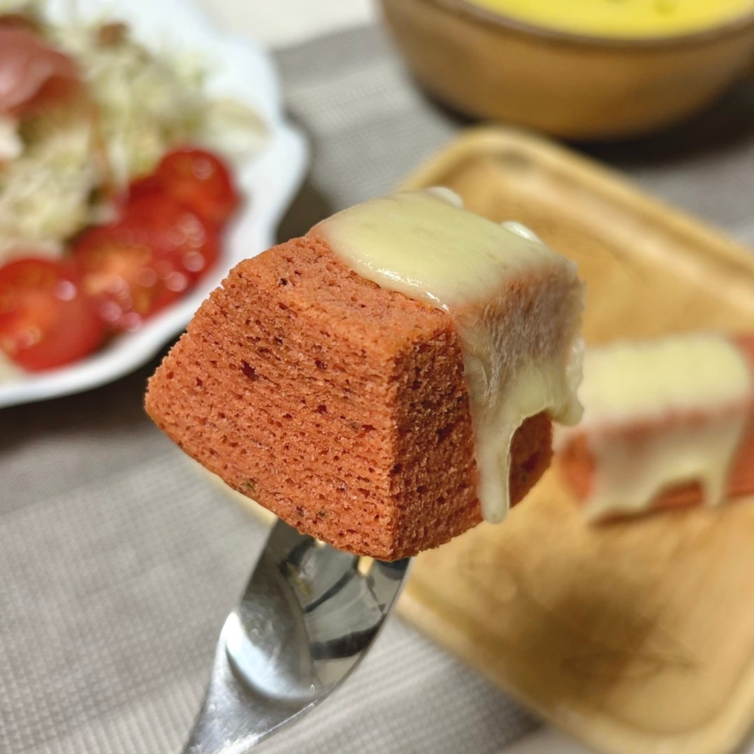 チーズをのせた「食物繊維がとれるバウム　トマト＆バジル」を食べるイメージ画像