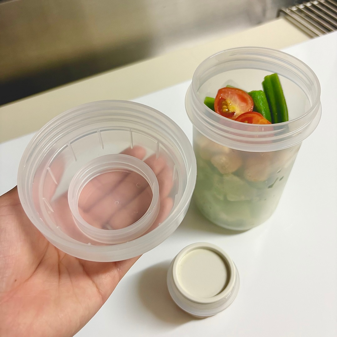 「トッピングカップ付き ランチカプセル」のふたを手に持つイメージ画像