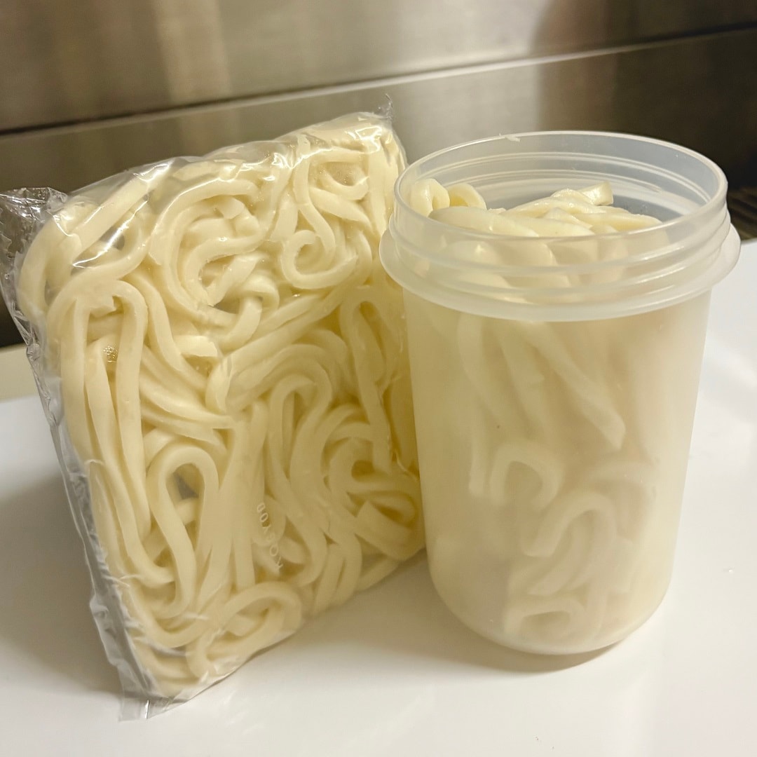 「トッピングカップ付き ランチカプセル」にうどんを入れているイメージ画像