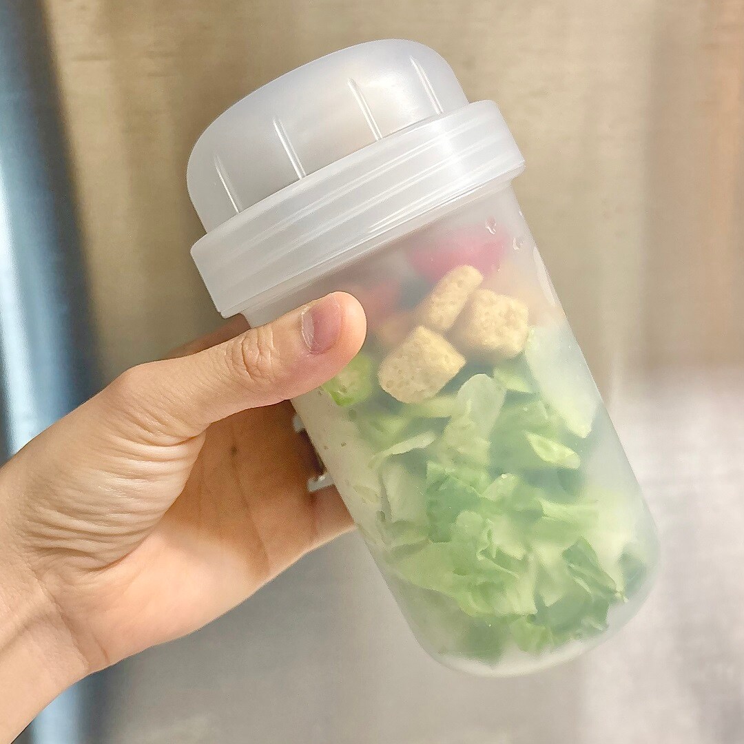 「トッピングカップ付き ランチカプセル」を手に持ったイメージ画像