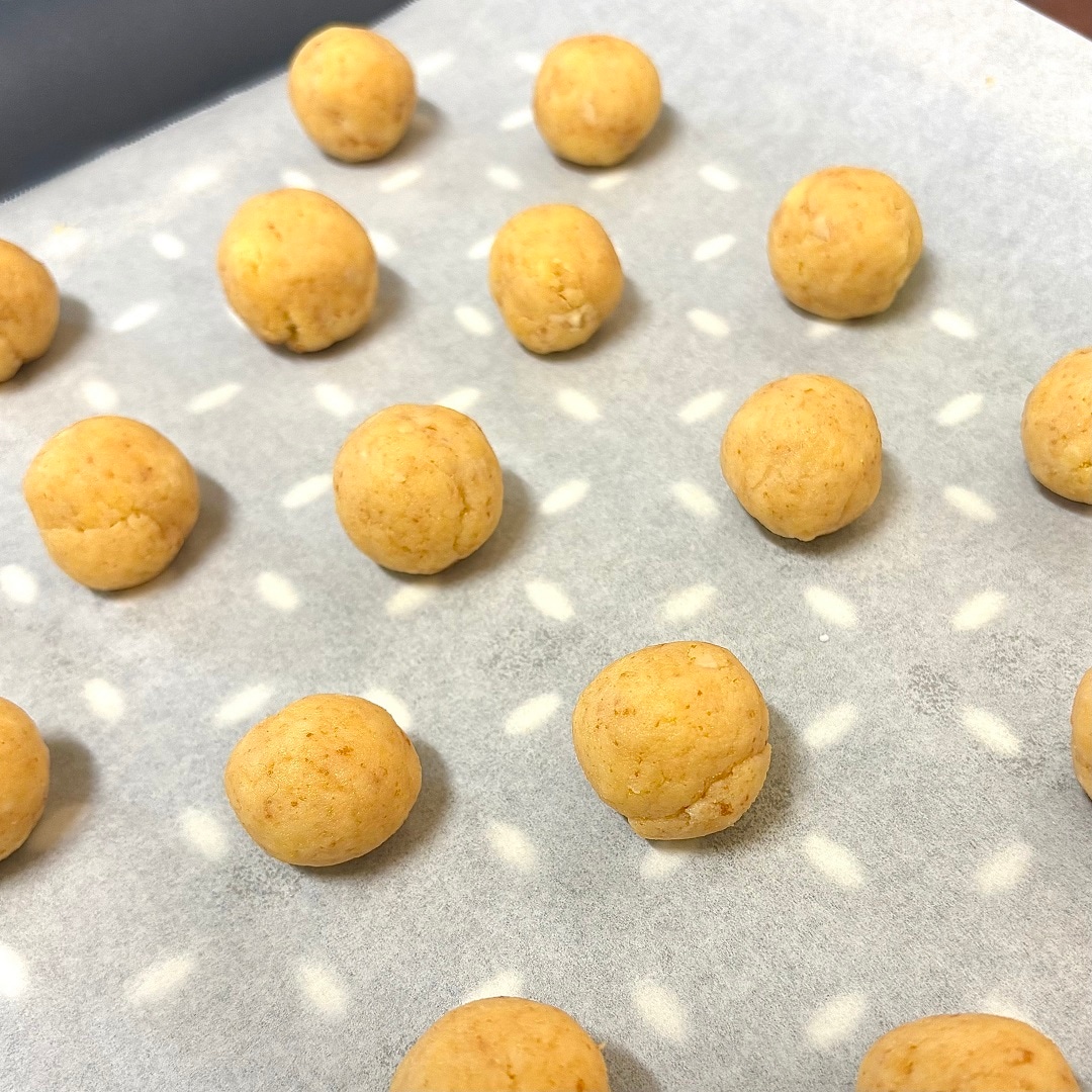 手で丸めた生地をトレーの上に並べているイメージ画像