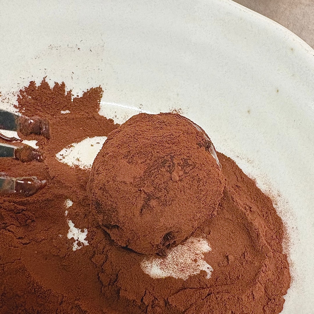 チョコレートでコーディングした生地にココアパウダーをまぶす様子