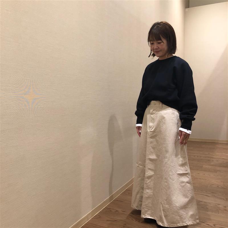 黒いスウェットシャツと白のカポックスカートを着用している女性の写真