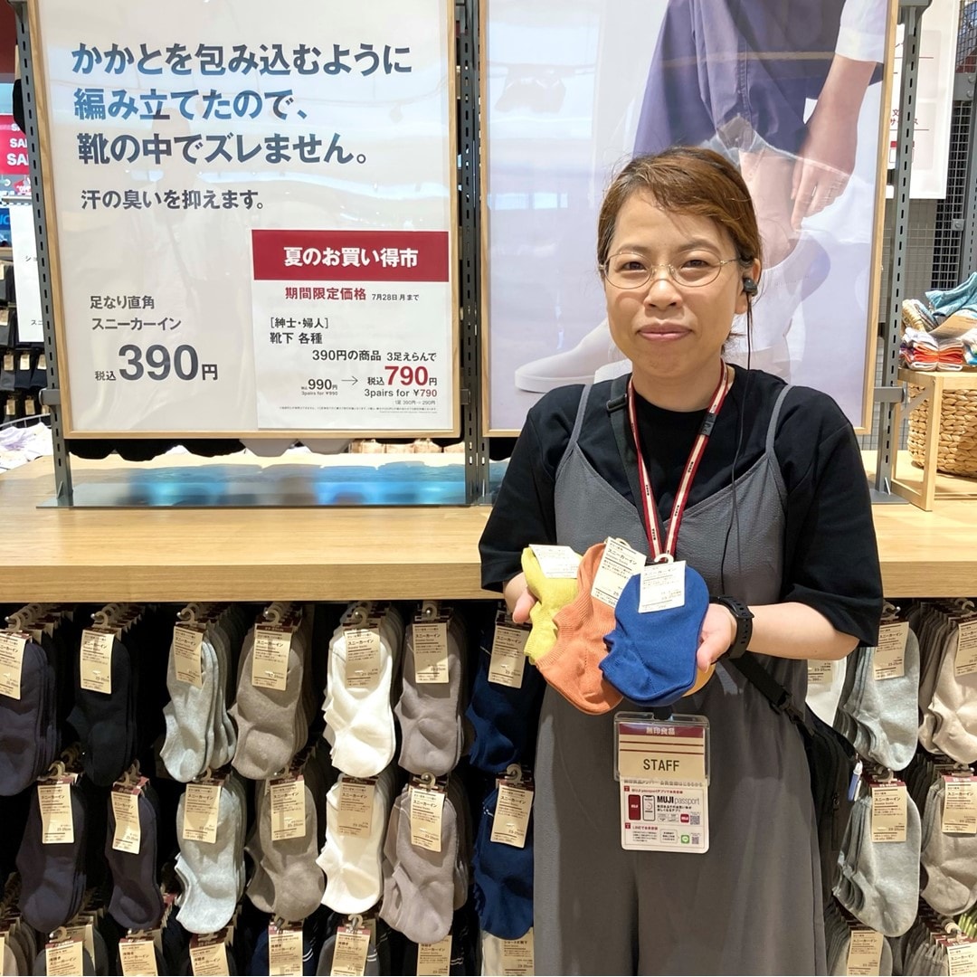靴下３足を持つスタッフの写真です。