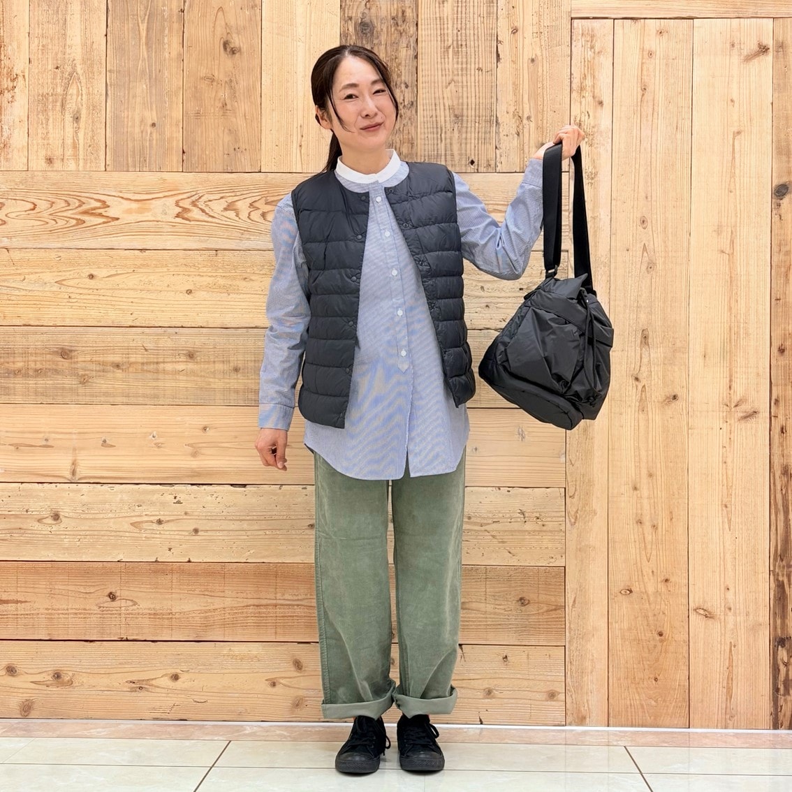 コーデュロイパンツにスタンドカラーロングシャツ、ベストを合わせたコーディネートのスタッフ写真です。