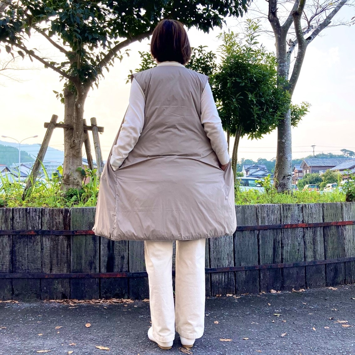 ハイネックセーターにノーカラーロングベストを合わせたコーディネートのスタッフ写真です。